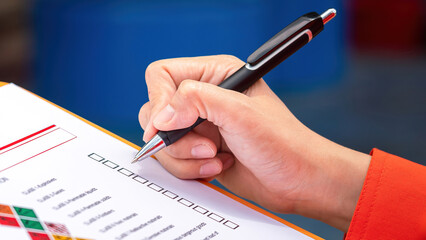 A safety engineer is using pen to rating the health risk assessment level of chemical hazardous material in the paperwork form. Industrial safety working scene, close-up and selecitve focus.