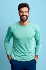 Wall Mural - smiling young man in sportswear looking at camera on blue background