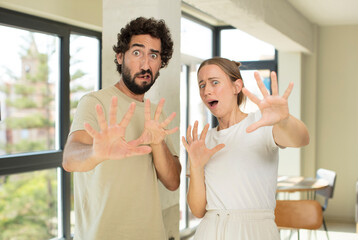 Canvas Print - young adult couple feeling terrified, backing off and screaming in horror and panic, reacting to a nightmare