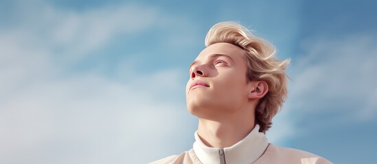 Wall Mural - Thoughtful young man daydreaming and gazing upward to empty area