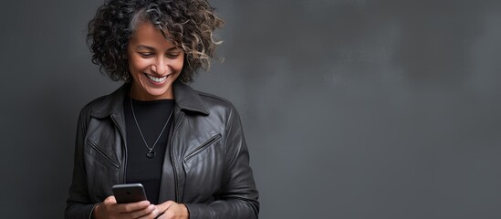 Cheerful middle aged lady typing on cellphone over grey background isolated with copy space