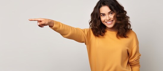 Wall Mural - Happy girl in casual clothes pointing on white background
