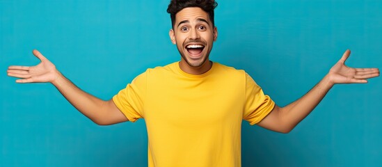 Aufkleber - Excited Hispanic man in blue shirt pointing with open palms and smiling presenting advertisement with copy space on yellow background