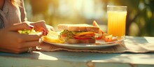 Plus Size Woman Having Lunch Outdoors Taking A Sandwich Slice With A Fork Orange Juice On The Table