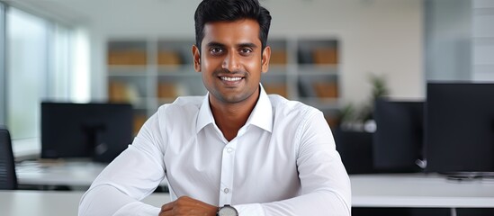 Canvas Print - Confident Indian businessman smiling at camera in office copy space