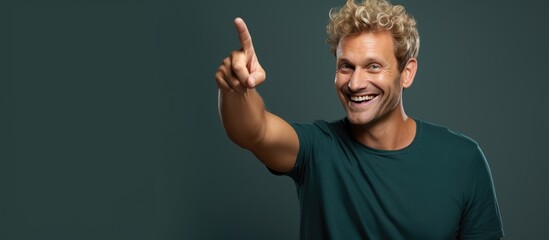 Wall Mural - A cheerful and happy adult man with blond hair pointing upwards towards empty space