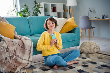 Canvas Print - Portrait of adorable lovely positive girl sitting on floor hold use smart phone enjoy free time inside room modern flat