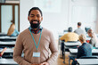© Drazen - Happy black professor during class with adult students in classroom looking at camera.