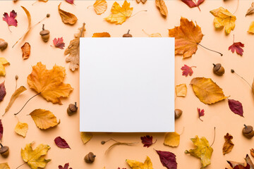 Wall Mural - Autumn composition with paper blank and dried leaves on table. Flat lay, top view, copy space