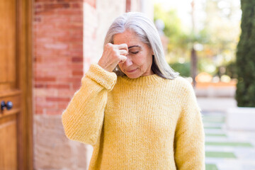 senior retired pretty white hair woman feeling stressed, unhappy and frustrated, touching forehead and suffering migraine of severe headache