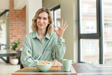 pretty woman feeling happy, showing approval with okay gesture. breakfast bowl concept