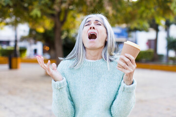 Sticker - pretty senior woman screaming with hands up in the air with a take away coffee