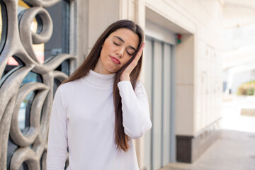 Wall Mural - pretty young adult woman feeling bored, frustrated and sleepy after a tiresome, dull and tedious task, holding face with hand