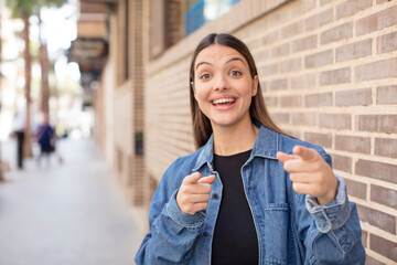 young pretty woman feeling happy, cool, satisfied, relaxed and successful, pointing at camera, choosing you