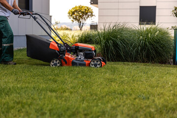 Cropped picture of a worker using a lawn mower to cut grass outside.