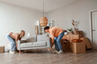 © Pixel-Shot - Young couple carrying sofa in room on moving day
