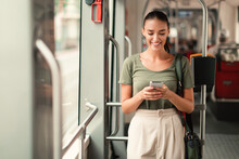 Joyful Passenger Woman Texting On Mobile Phone In Modern Tram
