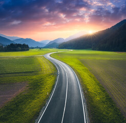 Wall Mural - aerial view of road in alpine mountain valley, green meadows at sunset in summer. top drone view of 