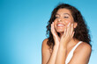 © Prostock-studio - Smiling young european curly lady enjoy cream and skin moisturizing, doing massage with hands