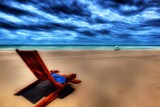 Fototapeta Tęcza - A Red Chair Sitting On Top Of A Sandy Beach