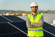 Happy solar panel installer with a green vest and safety helmet