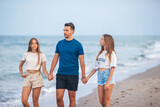 Fototapeta  - Portrait of father with his adorable daughters on the beach during their summer vacation