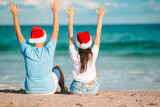 Fototapeta  - Christmas happy couple in Santa hats on beach vacation