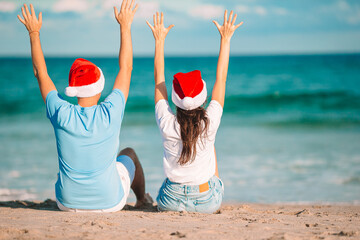 Wall Mural - Christmas happy couple in Santa hats on beach vacation