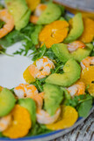 Fototapeta  - Green healthy vegan salad with arugula, avocado, shrimps and tangerines