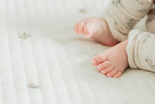 春の朝、マットで寝そべる日本人の赤ん坊のレッグウォーマーを着けた足