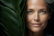 © Sergio - Beautiful middle aged woman model and big green leaves, portrait caucasian elderly lady looking at camera. Senior people and beauty, skincare concept