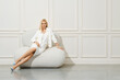 Stylish woman in total white outfit posing indoors