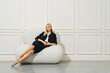 © boomeart - Tricky blonde woman in jacket and mini skirt is reclining on a soft large chair