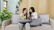 © itchaznong - Asian beautiful lesbian gay couple enjoy play game together in Livingroom. Two female friend sit on sofa in living room, feel happy to play joystick game at home.