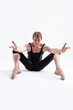 © danmorgan12 - Ballerino Dancer Sitting While Practising Legs and Arms Forward Stretching Exercices Before Training In Black Sportive Tights in Studio.