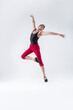© danmorgan12 - Ballet Ideas. Contemporary Ballet of Flexible Athletic Man Posing in Red Tights in Dance Pose With Hands Lifted on One Feet in Studio on White.