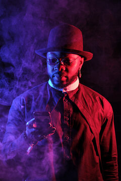 Stylish African American male with mobile phone in neon lights