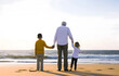 © May - Grandfather walking with grandchildren at beach. Concept of grandfather day, grandparents day