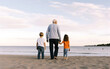 © May - Grandfather walking with grandchildren at beach. Concept of grandfather day, grandparents day