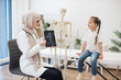© sofiko14 - Pediatrician with MRI on tablet consulting girl in clinic