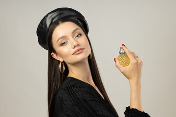 Wall Mural - Young woman in beret with perfume bottle on white background