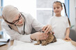 © sofiko14 - Woman checking cat's teeth on vet visit with girl in clinic