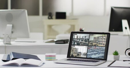 Poster - Laptop with four security camera views on screen on desk in empty modern office space, slow motion