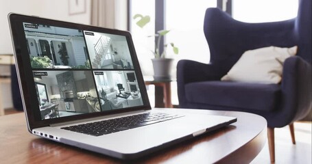 Canvas Print - Laptop on coffee table in living room with home security camera views on screens, slow motion