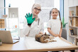© sofiko14 - Girl and vet in pet grooming glove smiling at camera