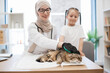 © sofiko14 - Arabian vet stroking cat with grooming glove near owner