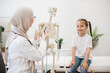 © sofiko14 - Family doctor illustrating bones to girl via skeleton model