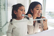 © Azee/peopleimages.com - Mother, child and brushing teeth in dental cleaning hygiene, morning routine or healthcare together by mirror in bathroom. Happy mom and daughter mouth in tooth whitening, oral or gum care at home