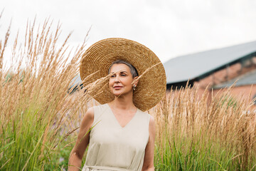 Wall Mural - Aged female in a straw hat walking on a wheat field