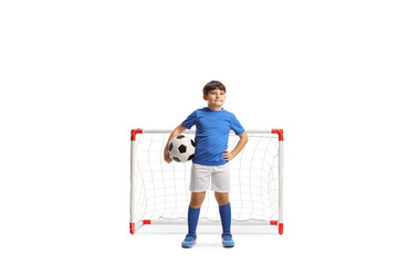 Wall Mural - Full length portrait of a boy in sports jersey holding a soccer ball and posing in front of a mini goal